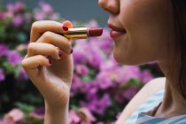Jeune femme asiatique à l'aide de rouge à lèvres, gros plan — Photo de stock