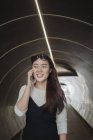 Китаянка с длинными волосами говорит по смартфону в тоннеле — стоковое фото