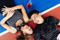 Happy asian sporty couple lying on track together — Stock Photo