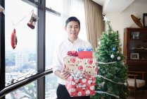 Feliz asiático hombre holding regalos - foto de stock