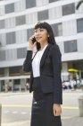 Asian business woman on phone at city street — Stock Photo