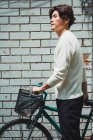 Молодий азіатський чоловік ходить з велосипедом на вулиці — стокове фото