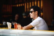 Jovem atraente asiático homem no café, vista lateral — Fotografia de Stock