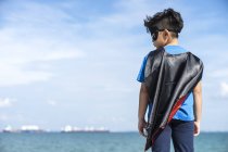Superhero kid checking his left side, rear view — Stock Photo