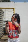 Asian woman with headphones wearing sunglassesusing phone — Stock Photo