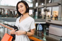 Jovem bela mulher asiática com sacos no shopping — Fotografia de Stock
