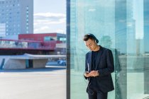Молодий азіатський чоловік з гарнітурою і смартфоном на парковці — стокове фото