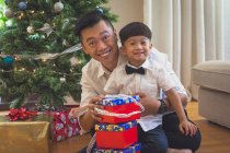 Vater und Sohn sitzen auf dem Boden und öffnen Weihnachtsgeschenke — Stockfoto
