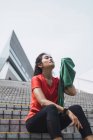 Young asian sporty woman using towel on stairs — Stock Photo