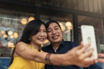 Feliz joven asiático pareja tomando selfie en café - foto de stock
