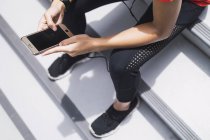 Обрезанный образ женщины с помощью смартфона на лестнице — стоковое фото