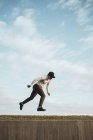 Junger asiatischer Mann macht Parkour gegen blauen Himmel — Stockfoto