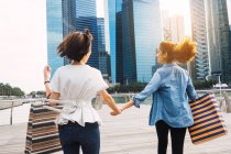 Young beautiful asian women together in urban city holding hands and running — Stock Photo