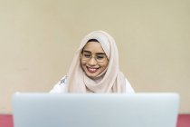 Jovem asiático muçulmano mulher usando laptop dentro de casa — Fotografia de Stock