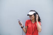 Молода азіатська спортивна жінка використовує навушники і розумний — стокове фото