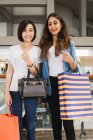 Giovani belle donne asiatiche insieme nella città urbana con borse della spesa — Foto stock