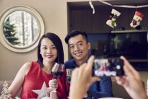 Happy asian family celebrating christmas together and taking photo at table — Stock Photo