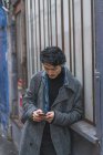 Молодий привабливий випадковий азіатський чоловік використовує смартфон на відкритому повітрі — стокове фото