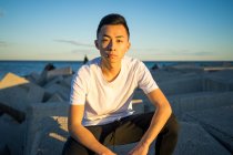 Retrato de joven asiático hombre sentado y mirando a la cámara - foto de stock