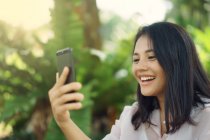 Happy asian woman taking selfie in park — Stock Photo