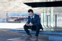 Молодий азіатський чоловік використовує смартфон у місті — стокове фото