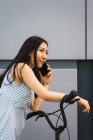 Jovem mulher asiática com bicicleta usando smartphone — Fotografia de Stock