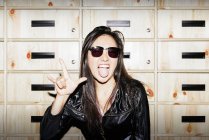 Jeune asiatique femme en lunettes de soleil montrant rock geste — Photo de stock