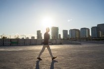 Вид збоку молодого азіатського чоловіка, що ходить у місті на заході сонця — стокове фото