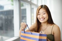 Giovane donna asiatica nel centro commerciale sorridente con gli occhi chiusi — Foto stock