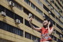 Asiatico turista donna taking selfie contro building — Foto stock