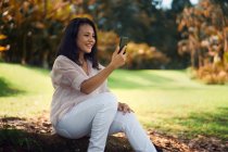 Felice donna asiatica utilizzando smartphone nel parco — Foto stock