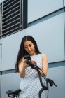 Giovane donna asiatica con bici utilizzando smartphone — Foto stock