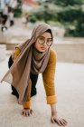 Joven asiático musulmán mujer en hijab posando en piso - foto de stock