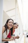 Young asian female friends with coffee at food court — Stock Photo