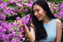 Jeune asiatique femme toucher fleurs — Photo de stock