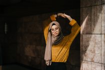 Joven asiático musulmán mujer en hijab posando por construcción - foto de stock