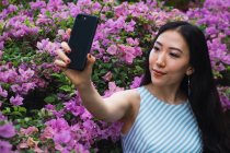 Jovem asiático mulher tomando selfie com flores — Fotografia de Stock
