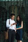 Young adult business couple using smartphone outdoors — Stock Photo