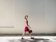 Mulher chinesa andando contra a parede branca — Fotografia de Stock
