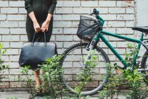 Jeune asiatique femme debout avec sac à côté de vélo — Photo de stock