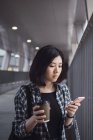 Joven hermosa asiático chica en casual ropa usando smartphone en ciudad calles - foto de stock