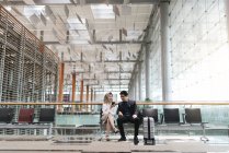 Jovem asiático casal de empresários usando smartphone no aeroporto — Fotografia de Stock