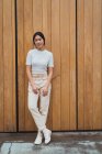 Молода приваблива азіатська жінка стоїть на дерев'яній стіні — стокове фото