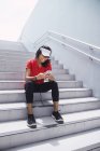 Молода азіатська спортивна жінка використовує навушники і розумний на сходах — стокове фото