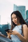 Young asian woman using smartphone against skyscrapers — Stock Photo