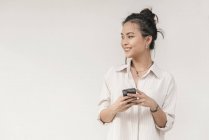 Молодая азиатка с улыбкой на смартфоне — стоковое фото