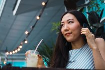 Young asian woman with drink and smartphone — Stock Photo