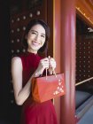 Femme chinoise avec sac à main rouge regardant la caméra — Photo de stock