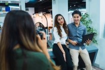 Young asian business people taking photo in modern office — Stock Photo