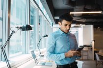 Junger erwachsener Geschäftsmann mit Smartphone im modernen Büro — Stockfoto